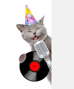 点击来源直接获取大图文件戴着生日帽的猫拿着复古麦克风和黑胶唱片,并从空板后面偷看白色背景下孤立摄影搞笑猫猫高清大图